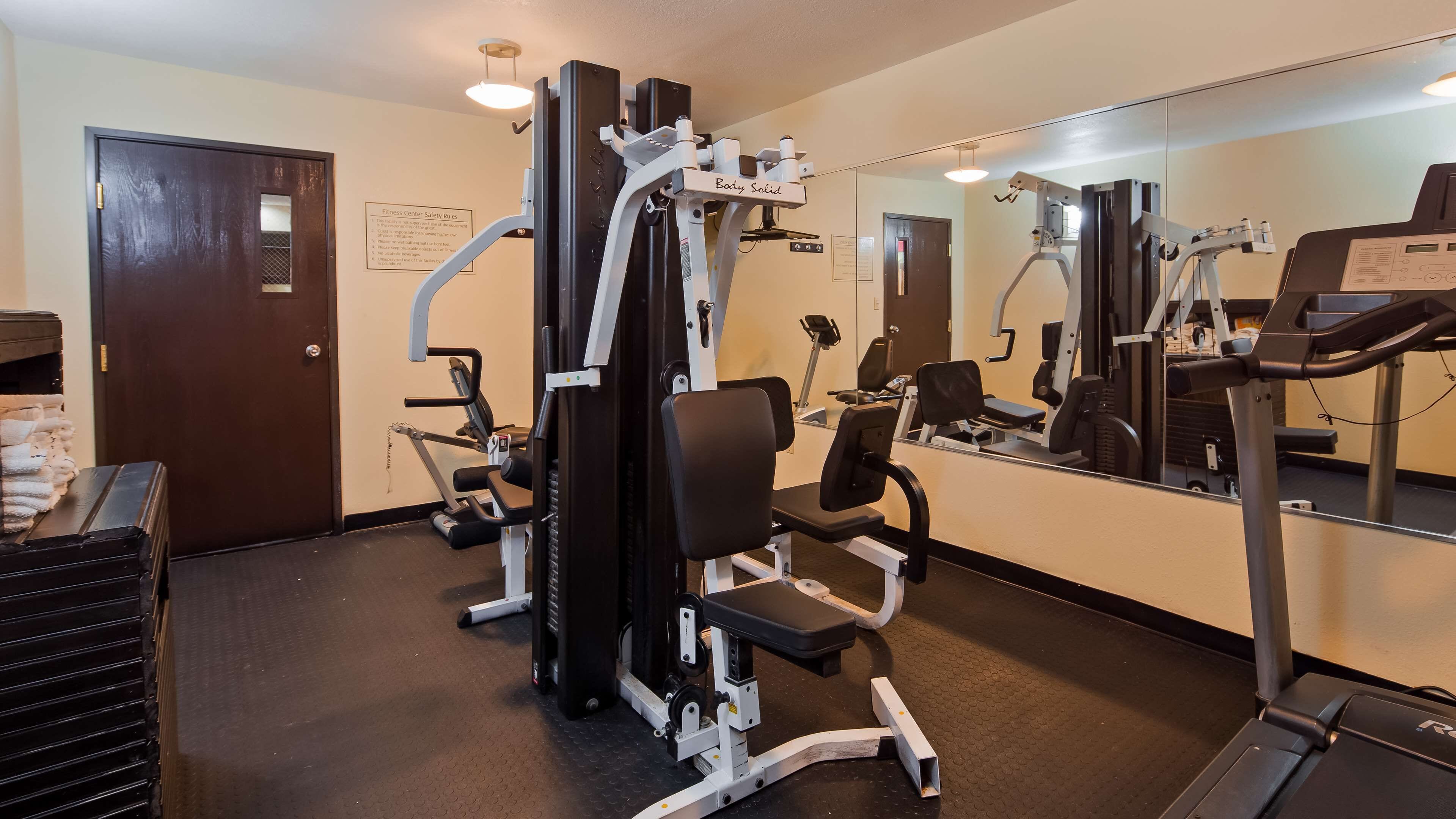 A fitness center with cardio machines, weight machines, and a mirrored wall.
