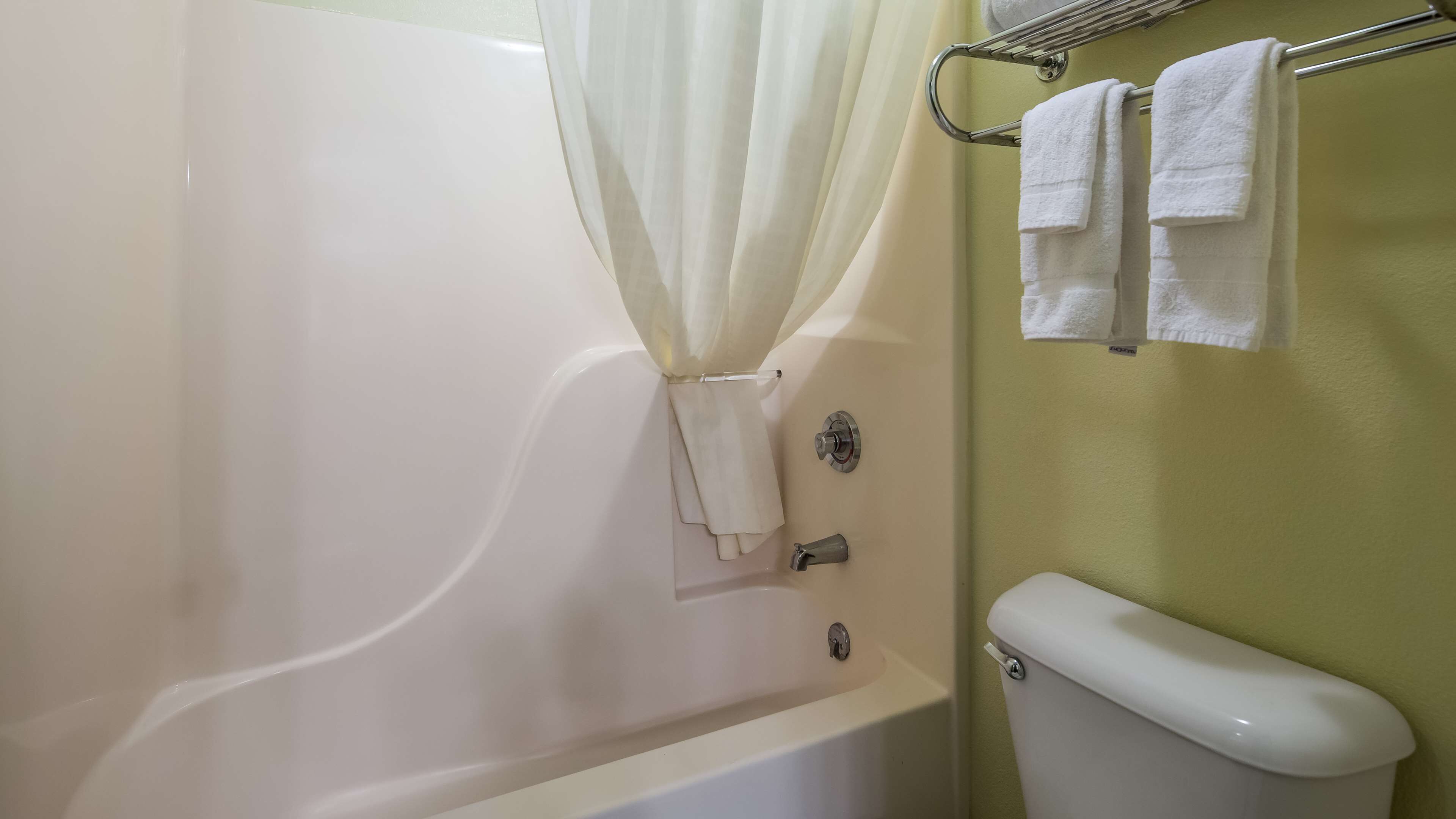 Un baño con una bañera, un inodoro y un perchero con toallas.