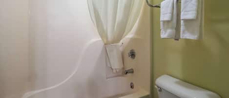 A bathroom with a bathtub, a toilet, and a towel rack with towels.