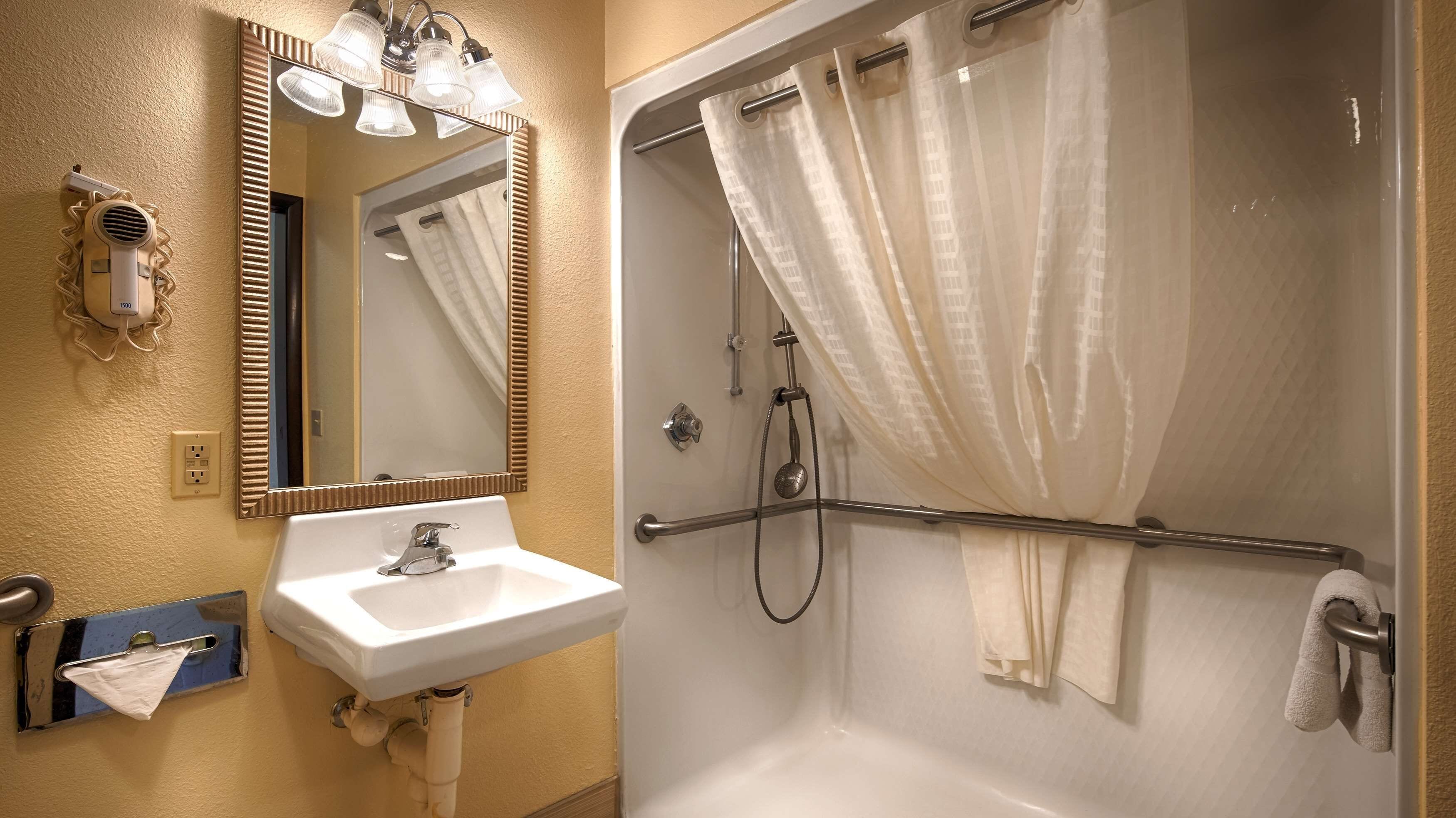 Une salle de bain avec un lavabo blanc, un miroir et une douche.