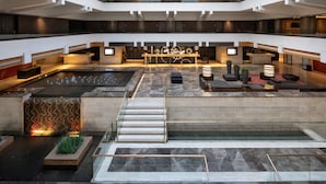 A spacious lobby with a central water feature, seating areas, and a reception desk. - Dan Jerusalem (Jerusalem)