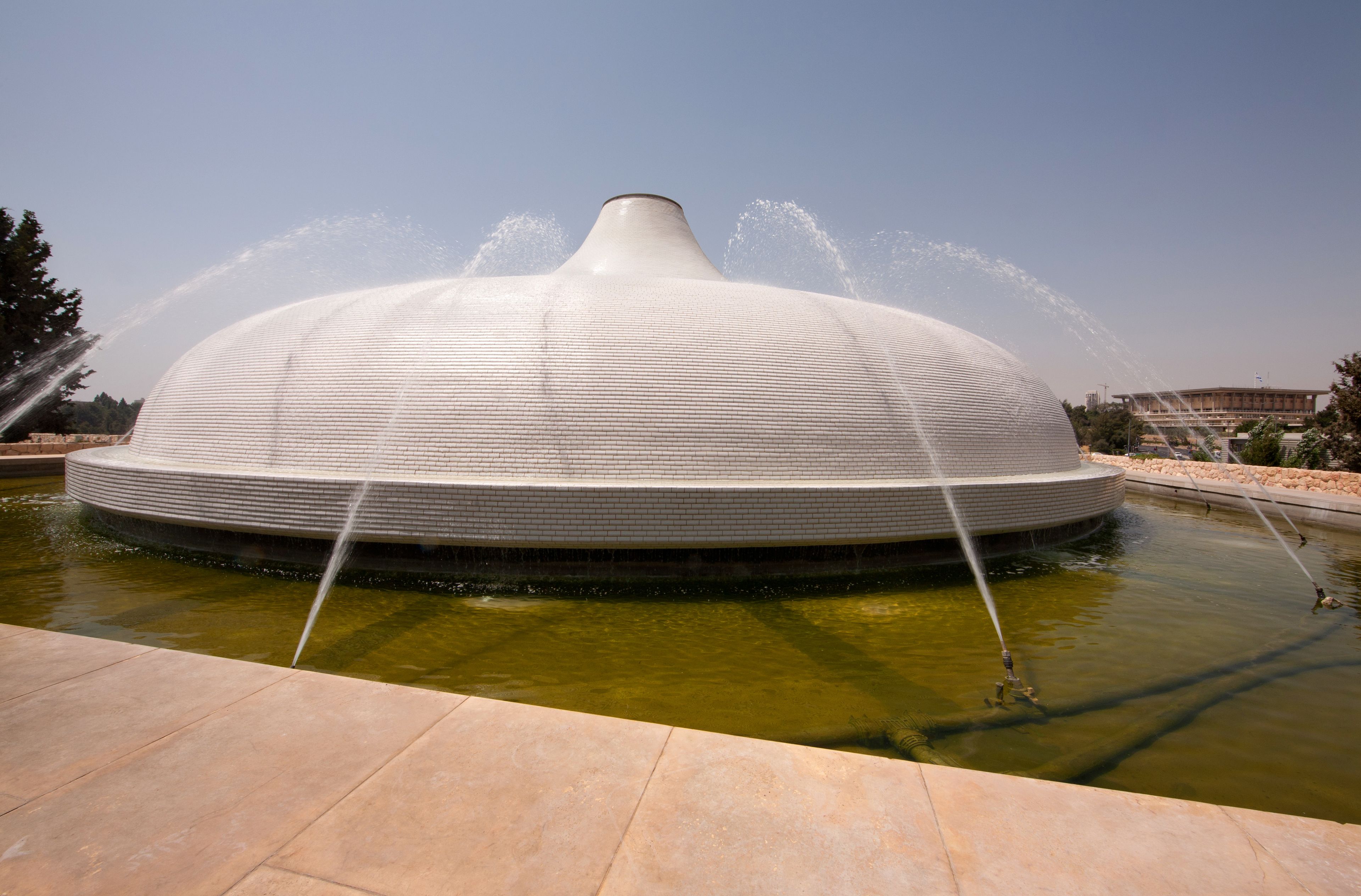 A large, white, dome-shaped water fountain with multiple jets spraying water into the air.