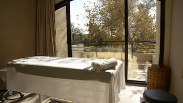 Enjoy a peaceful retreat with a view of the surrounding trees from the large window, featuring a comfortable bed and a cozy seating area.