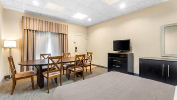 Una habitación de hotel con cama, escritorio con sillas, televisión y armario.
