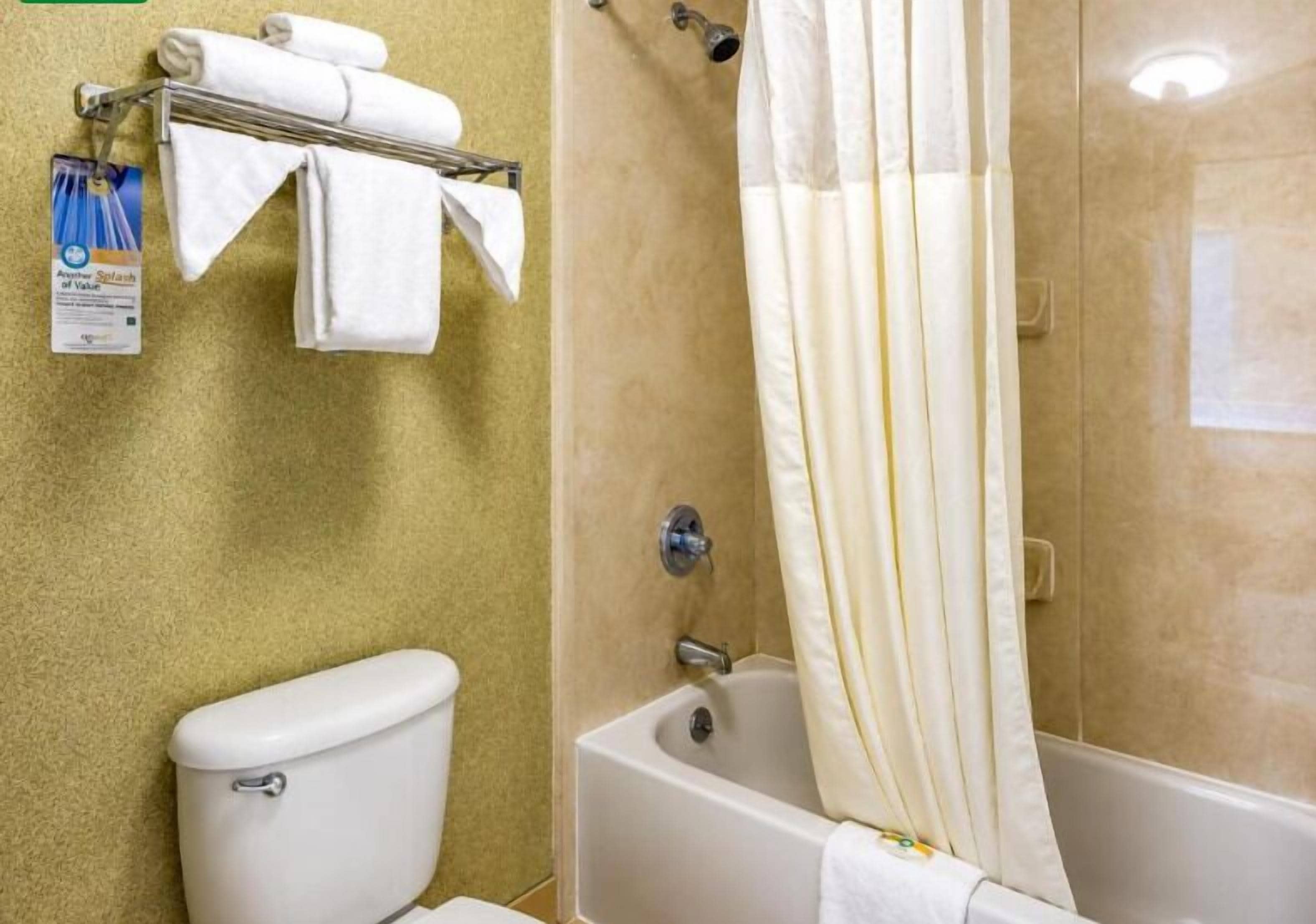 Un baño con inodoro, bañera y toallero con toallas dobladas.