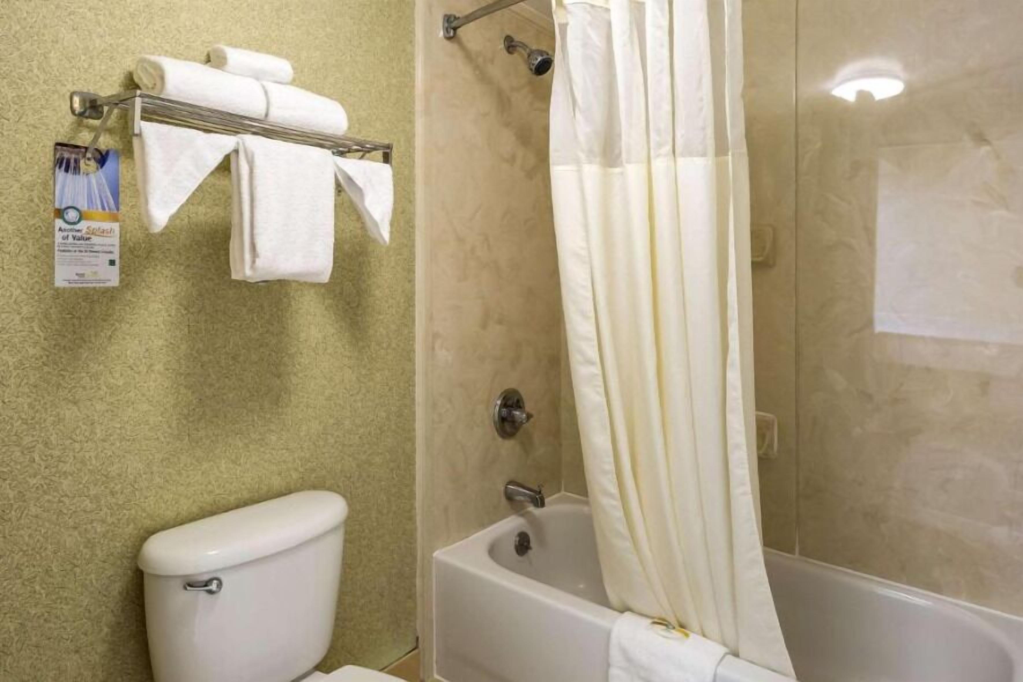 Un baño con inodoro, bañera y cortina de ducha.