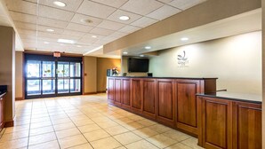 Un área de recepción con mostrador de madera, un televisor y un cartel que dice 'Quality Inn by Marriott'.