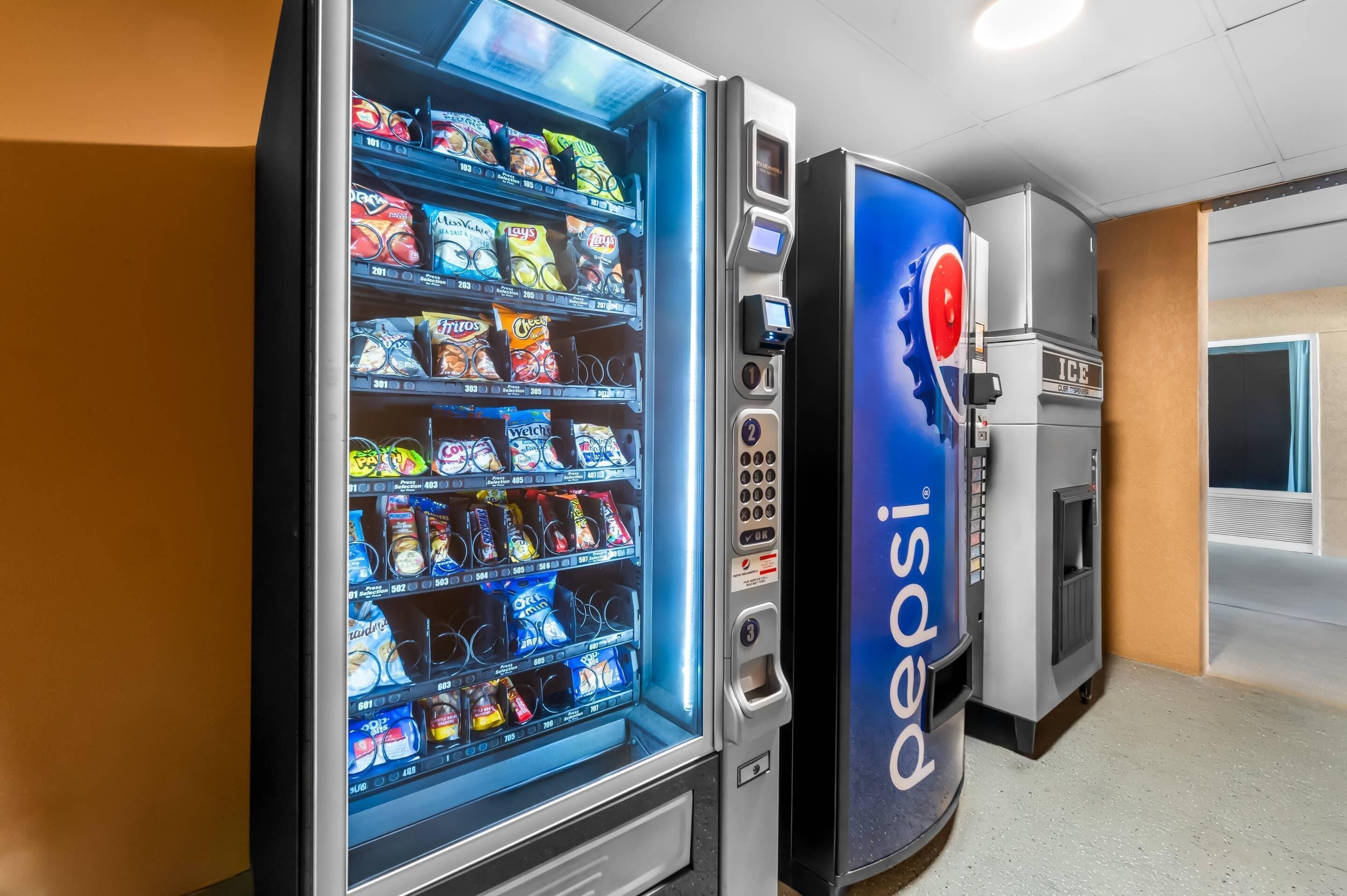 Een automaat met het Pepsi logo, een automaat voor snacks met diverse lekkernijen, en een waterdispenser.