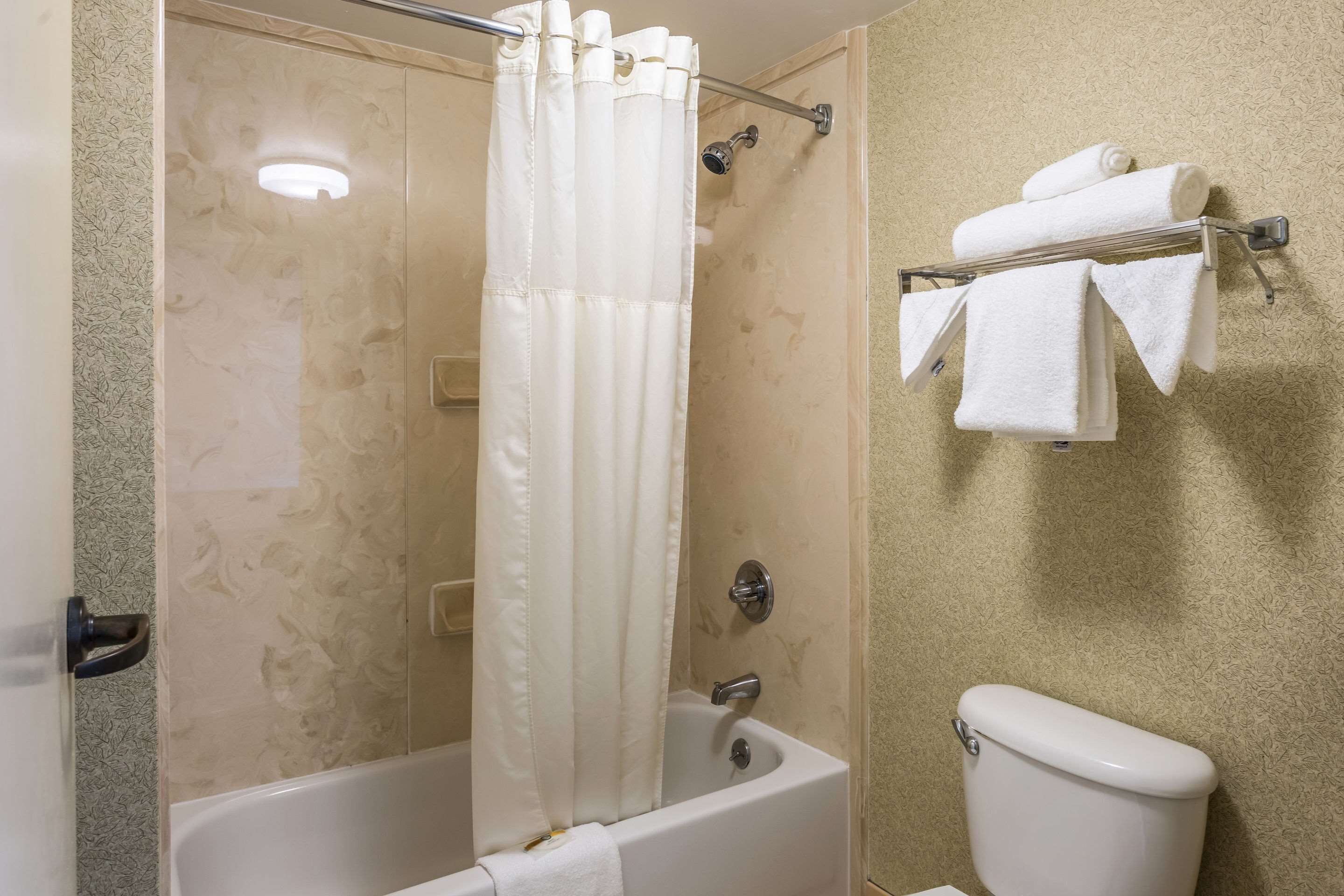 Un baño con bañera, cortina de ducha y toallero con toallas.