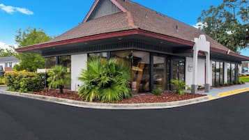A building with a red roof, large windows, and a covered entrance area.