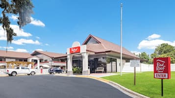 A Red Roof Inn with a covered parking area, a sign indicating private parking, and a clear blue sky.