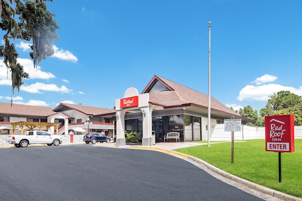 A Red Roof Inn with a covered parking area, a sign indicating private parking, and a clear blue sky. - Red Roof Inn Savannah - Southside/Midtown (Savannah)