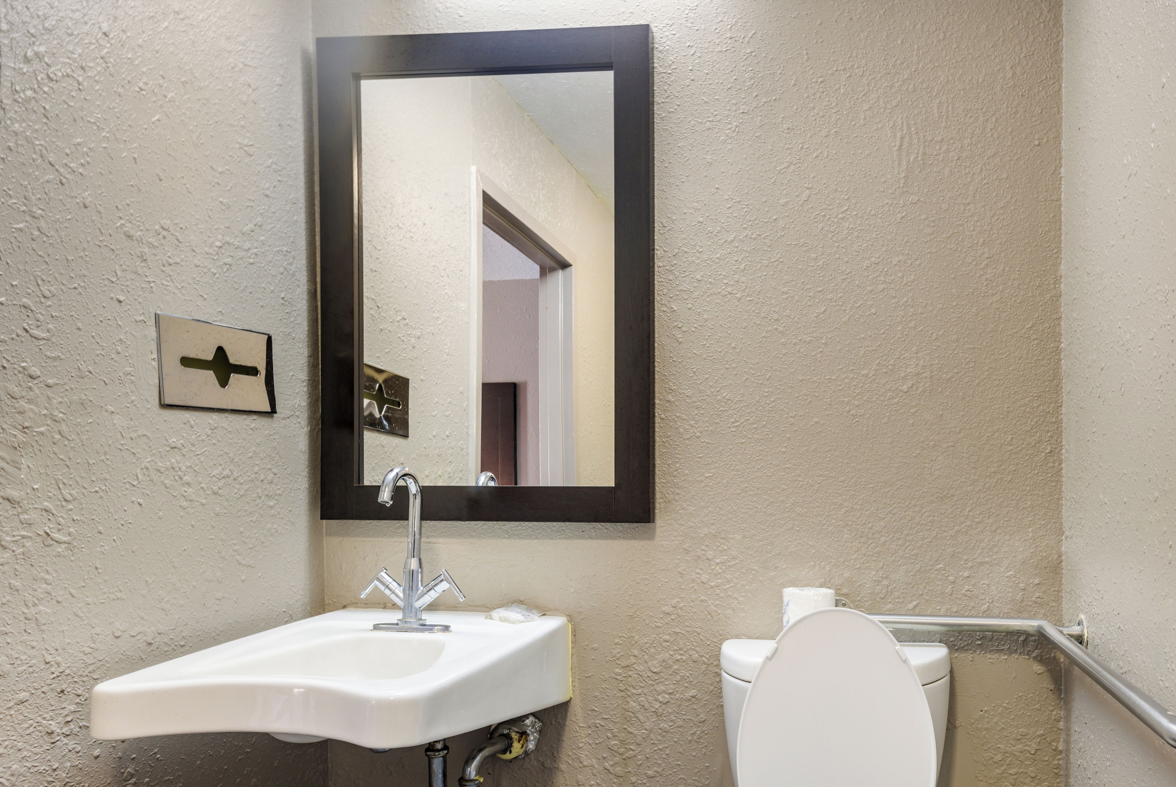 A bathroom with a white sink, a mirror, and a toilet.