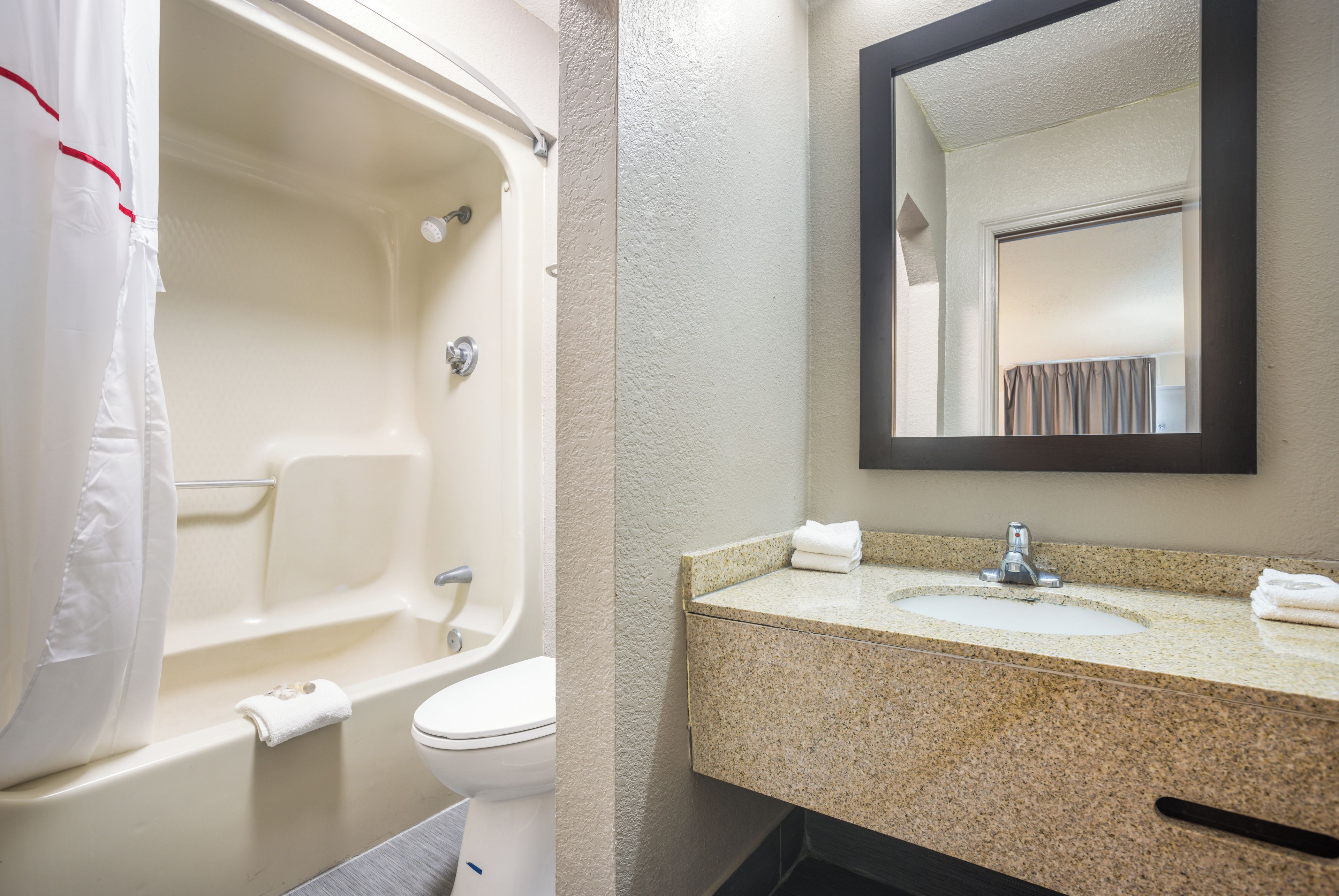 A bathroom with a bathtub, toilet, sink, and a mirror.