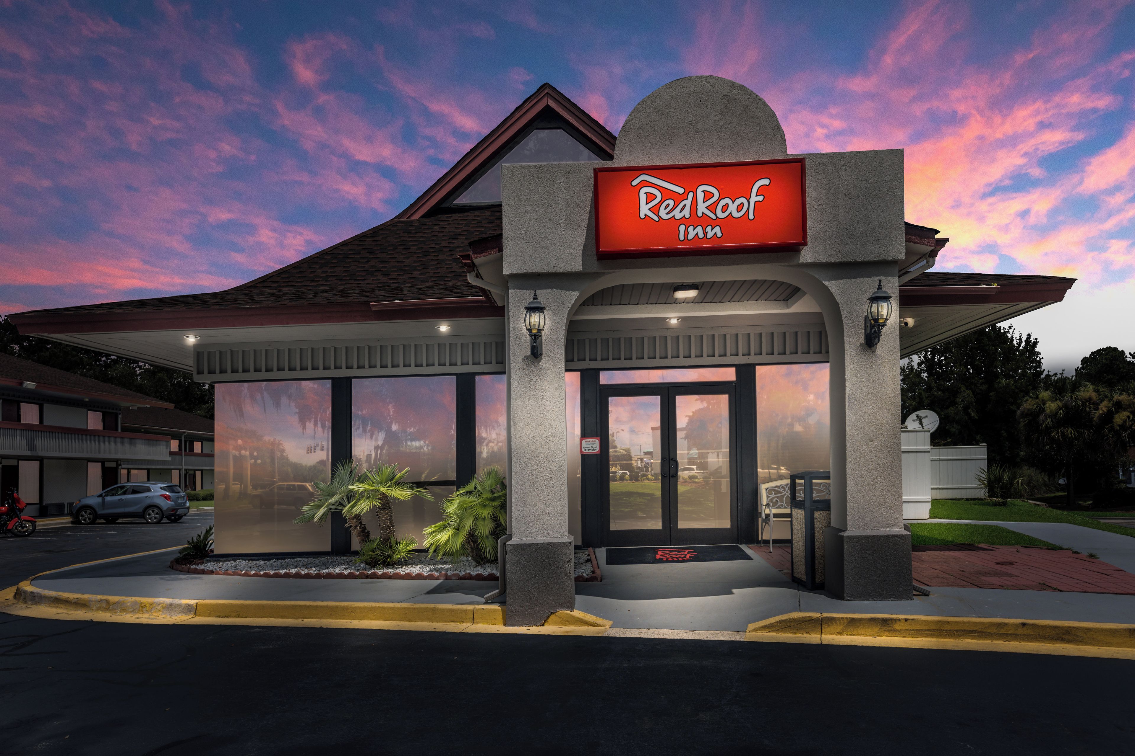 A Red Roof Inn with a covered entrance, large windows, and a clear sky.