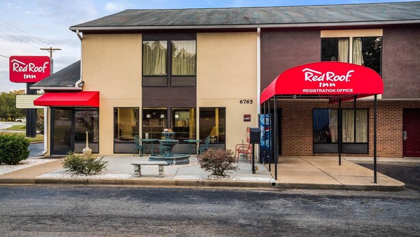 Een Red Roof Inn met een receptiebord, buiten zitplaatsen en een fontein.