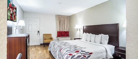 A hotel room with a bed, a desk, a chair, a television, and a window with curtains.