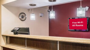 Een hotel receptie met een digitale klok, een kassa en een bordje dat gratis wifi aangeeft.