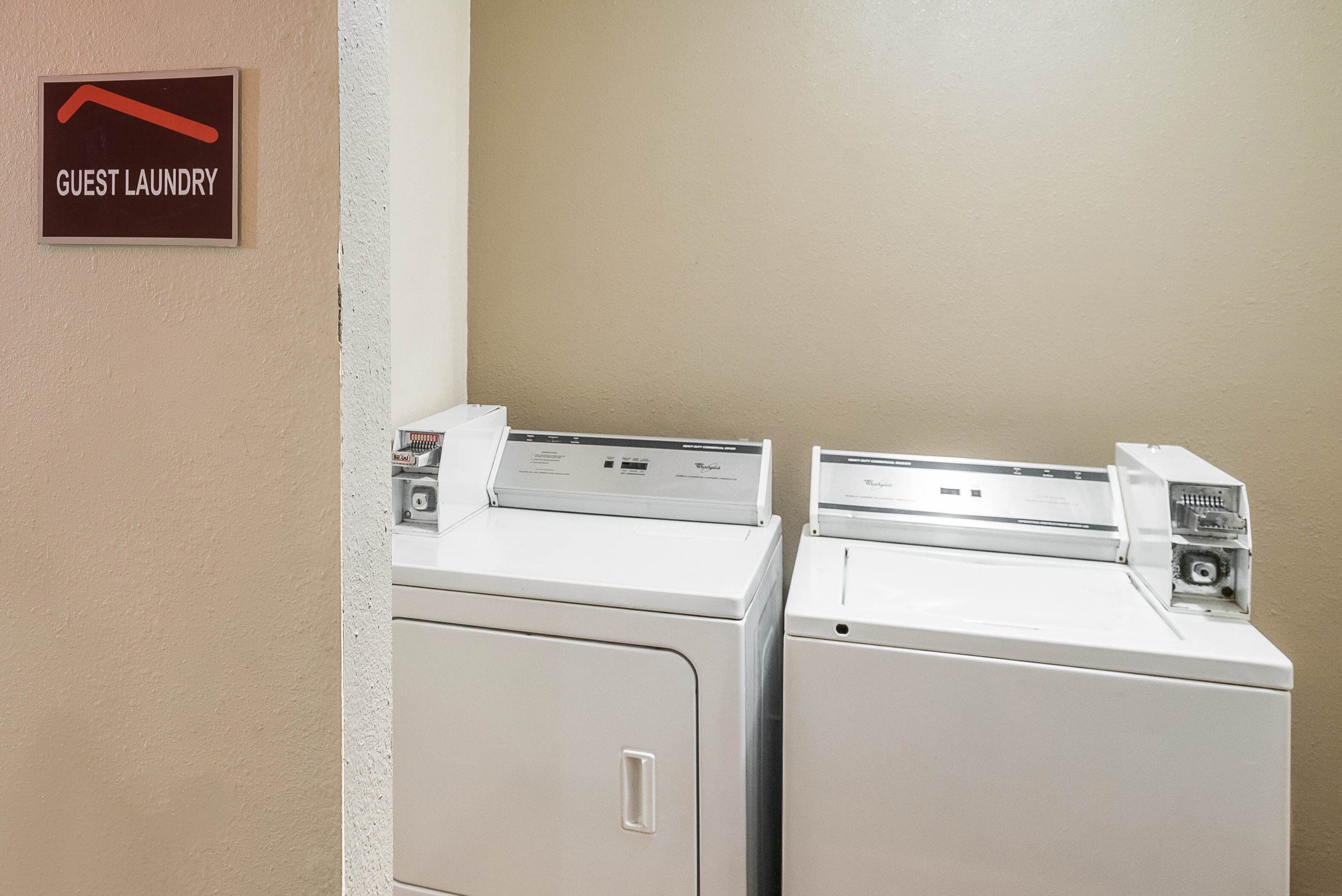 A guest laundry area with two washing machines and a sign indicating the location.