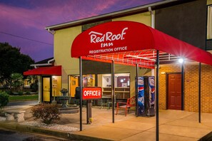 Een Red Roof Inn receptie met een rode luifel en een bordje dat het kantoor aangeeft.