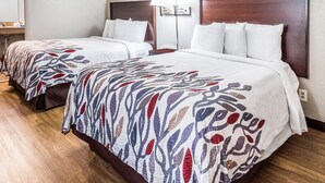 Ein Hotelzimmer mit zwei Betten, jeweils mit einem gemusterten Überwurf, einem Holzkopfende und einer Nachttischlampe.
