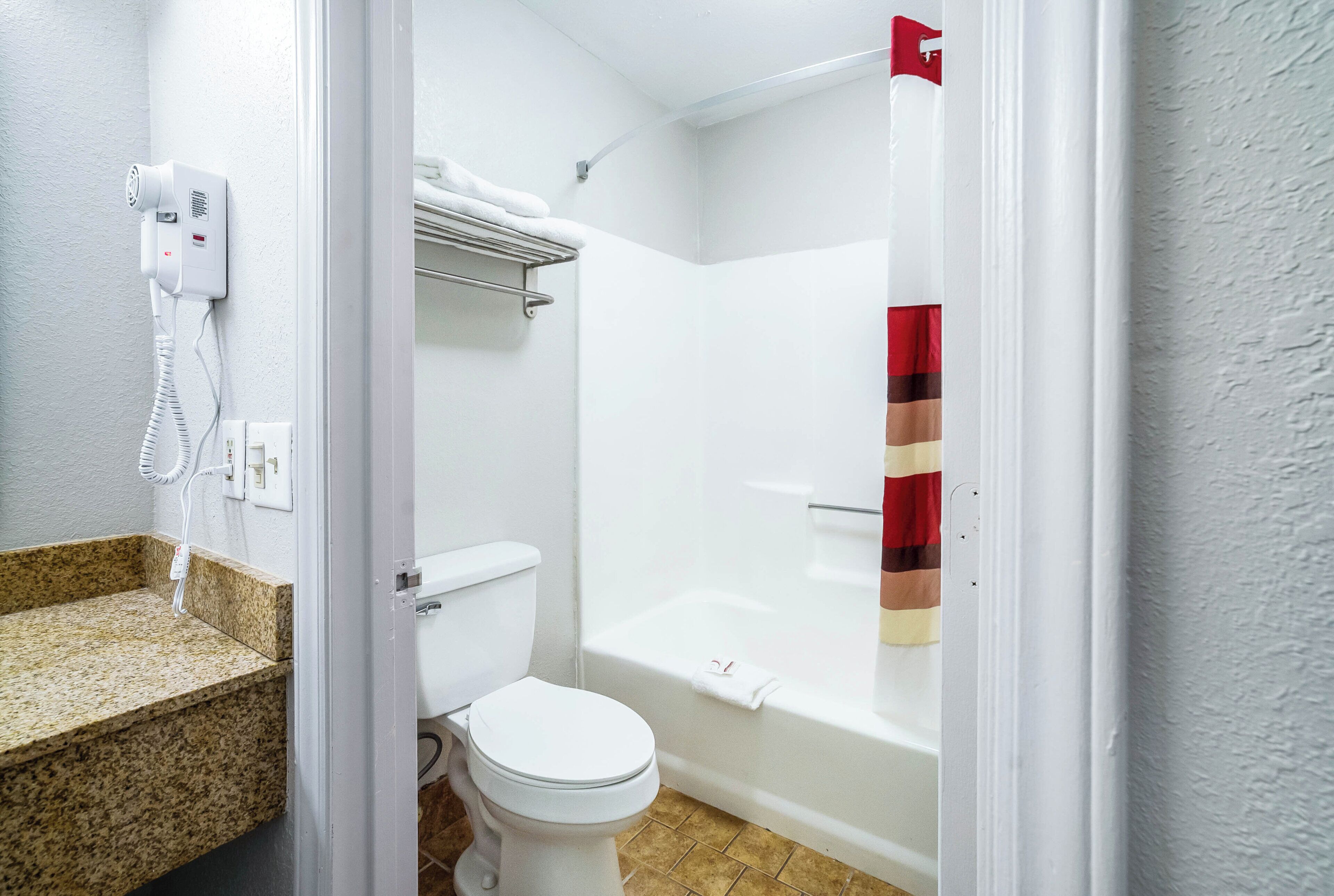 Een badkamer met toilet, douche en bad.