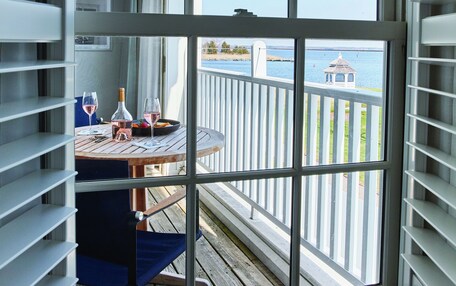 A room with a view of a wooden deck and a gazebo by the water.