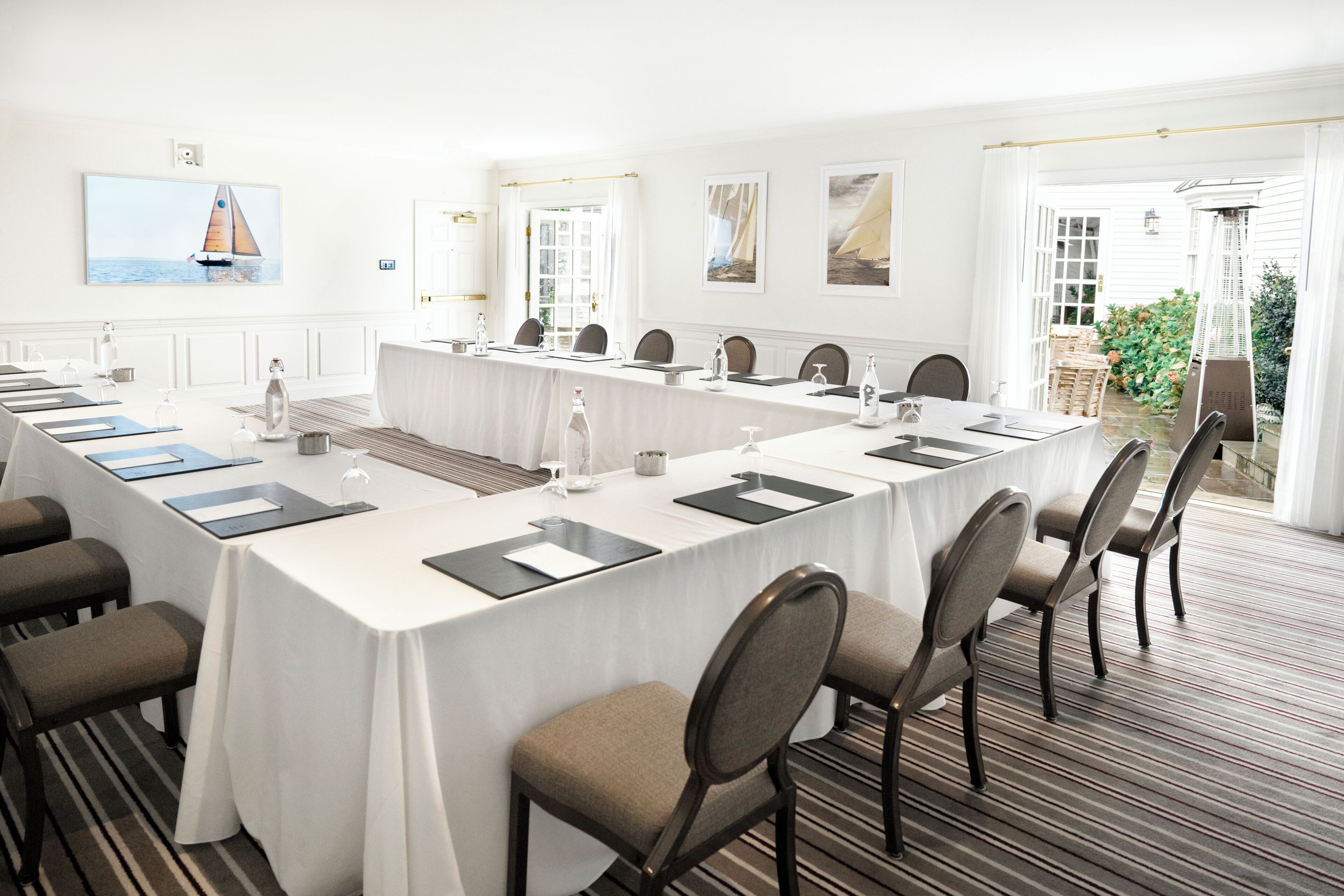 A conference room with a long table, chairs, and a view of the outdoors.