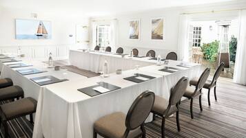 Un salón de conferencias con una larga mesa, sillas y vistas al exterior.