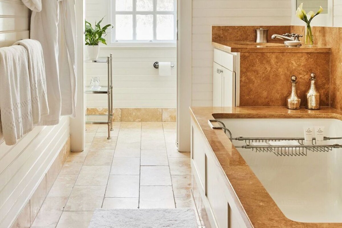 A bathroom with a bathtub, a sink with a marble countertop, and a shower area.