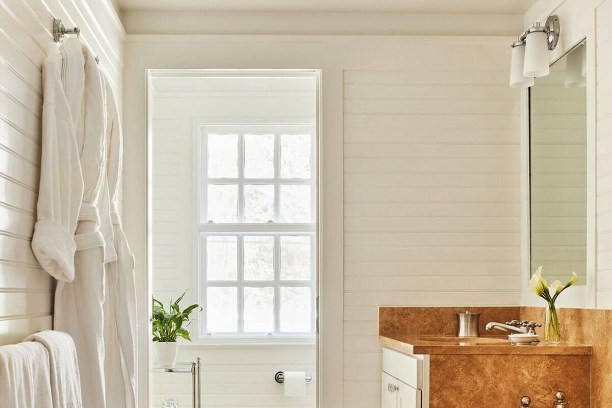 A bathroom with a large bathtub, a vanity with a mirror, and a window.
