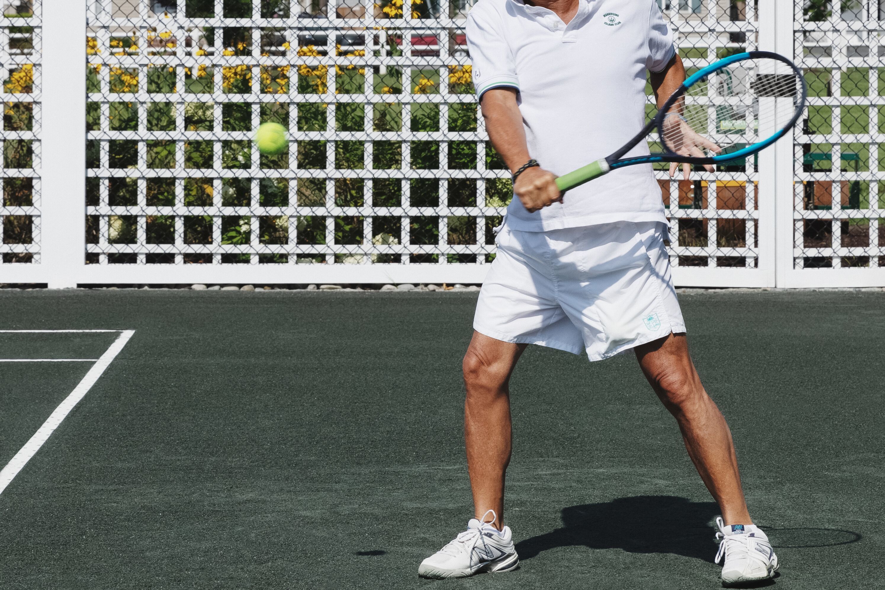 A tennis player on a court with a net and a fence in the background.