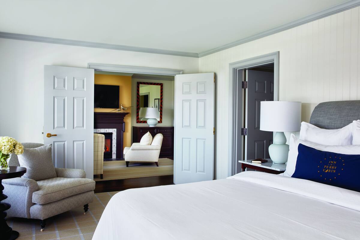 A hotel room with a large bed, a chair, a desk, and a television.
