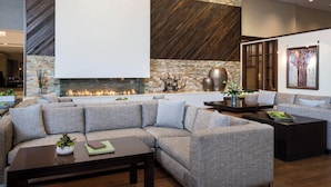 A modern living room with a sectional sofa, a fireplace, and a stone accent wall. - Provo Marriott Hotel & Conference Center (Provo)