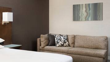 Ein Hotelzimmer mit Bett, einer Couch, einem kleinen Tisch und einem Wandbild.