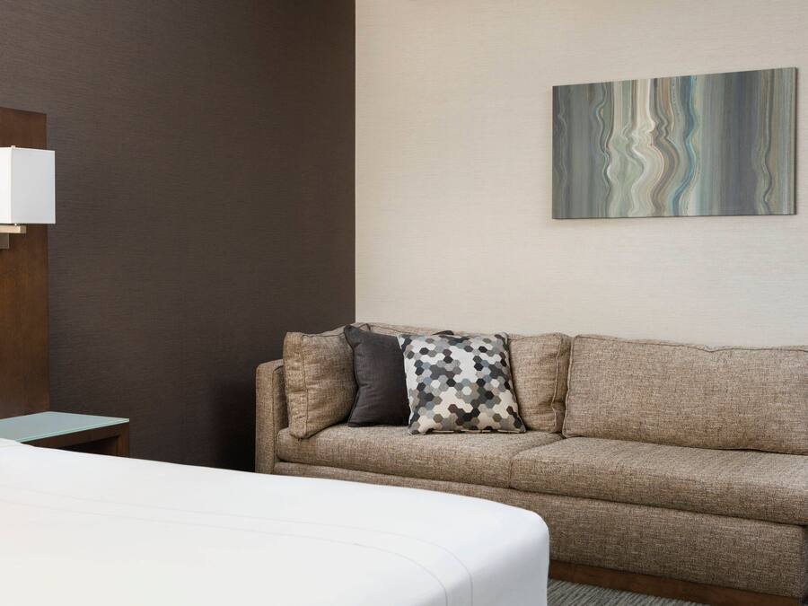 Ein Hotelzimmer mit Bett, einer Couch, einem kleinen Tisch und einem Wandbild.