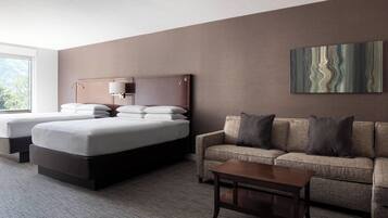 A hotel room with a bed, a sofa, a coffee table, and a painting on the wall.