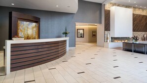A reception area with a curved reception desk, a large painting, and a fireplace.