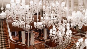 Un interior imponente con múltiples candelabros, una escalera y una zona de estar.