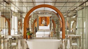 A modern bathroom with a large bathtub, mirrored walls, and a central mirror. - Le Royal Monceau - Raffles Paris (Paris)