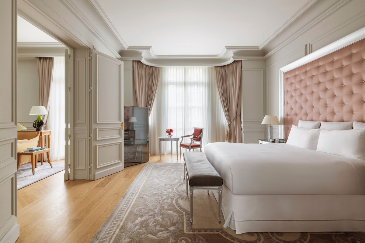 A hotel room with a large bed, a small desk, a chair, and a TV.