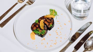Una mesa de comedor con un plato de comida, un vaso de agua y cubiertos.
