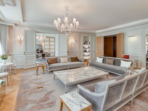A spacious living room with a marble coffee table, grey sofas, and a chandelier.