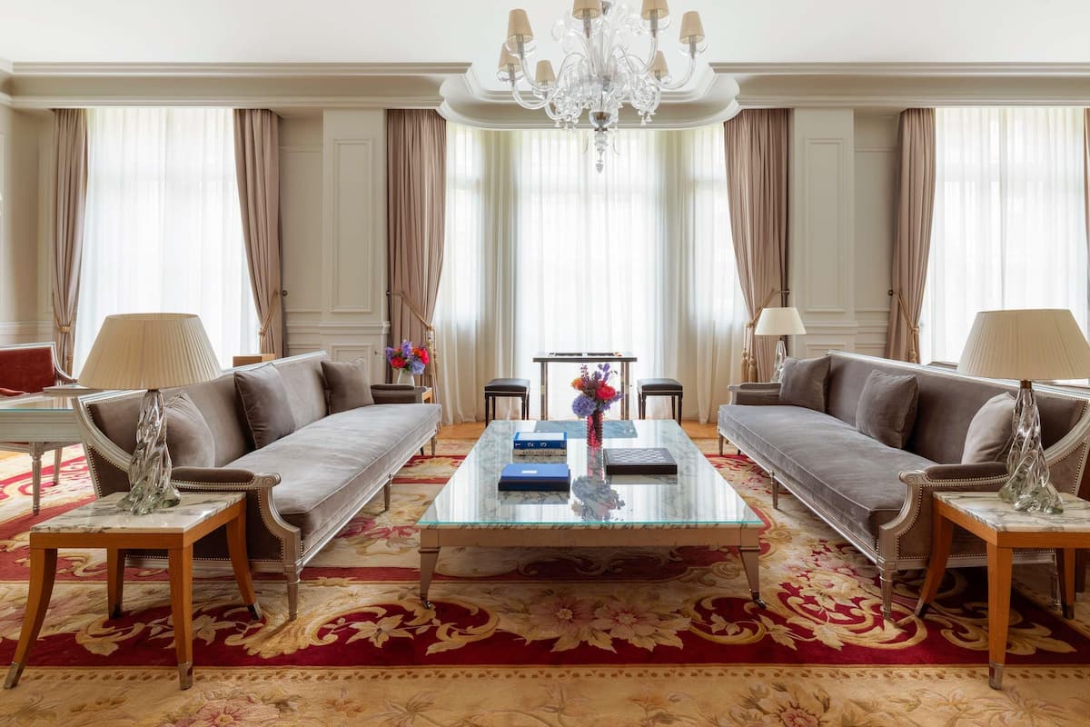 A spacious living room with two sofas, a coffee table, and a chandelier.