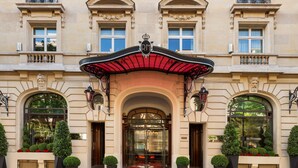 A classical building facade with a central entrance, arched windows, and a red awning. - Le Royal Monceau - Raffles Paris (Paris)