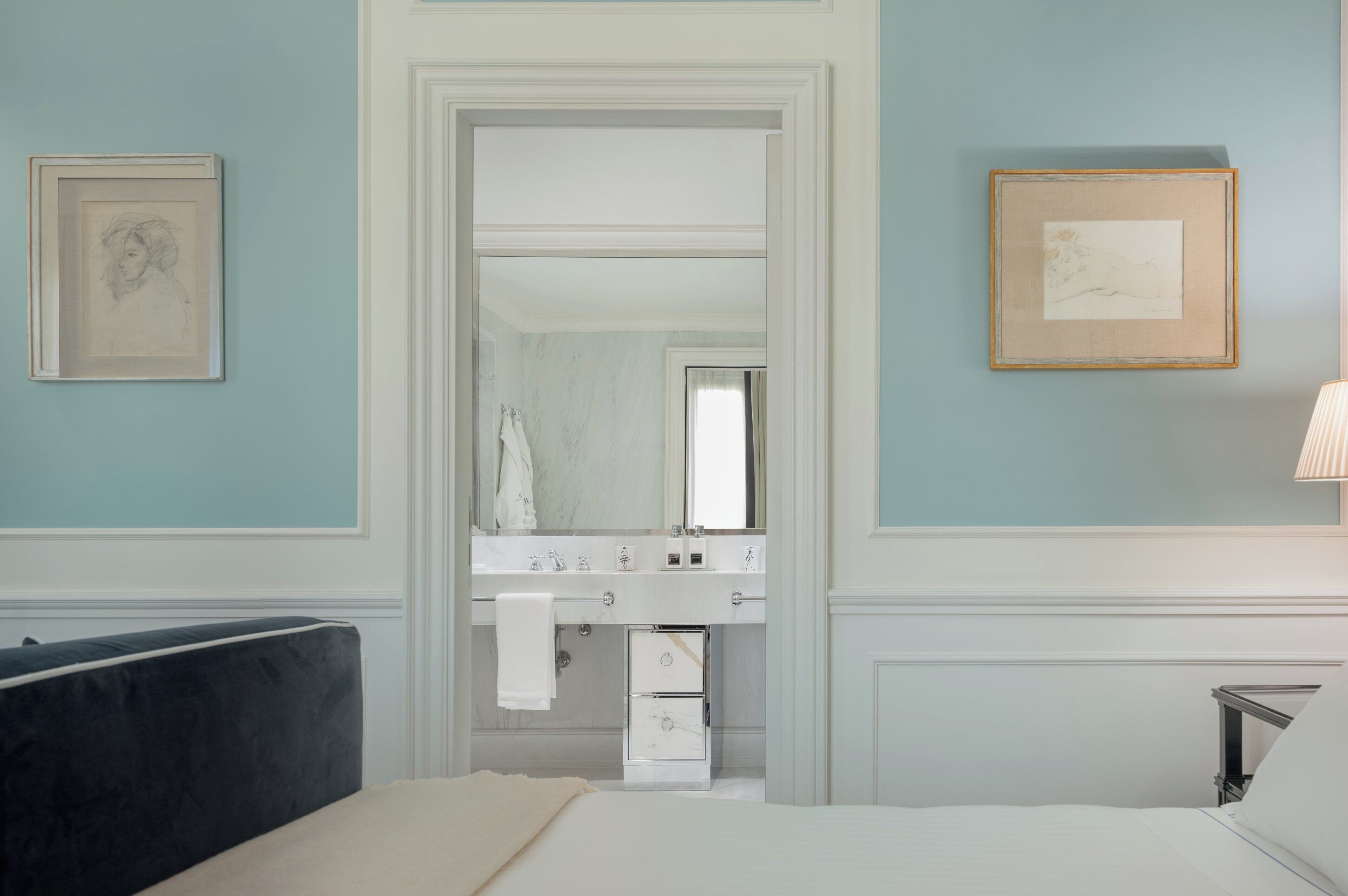 Ein Schlafzimmer mit Bett, Nachttisch, Kommode und einem Badezimmer mit Spiegel und Waschbecken.