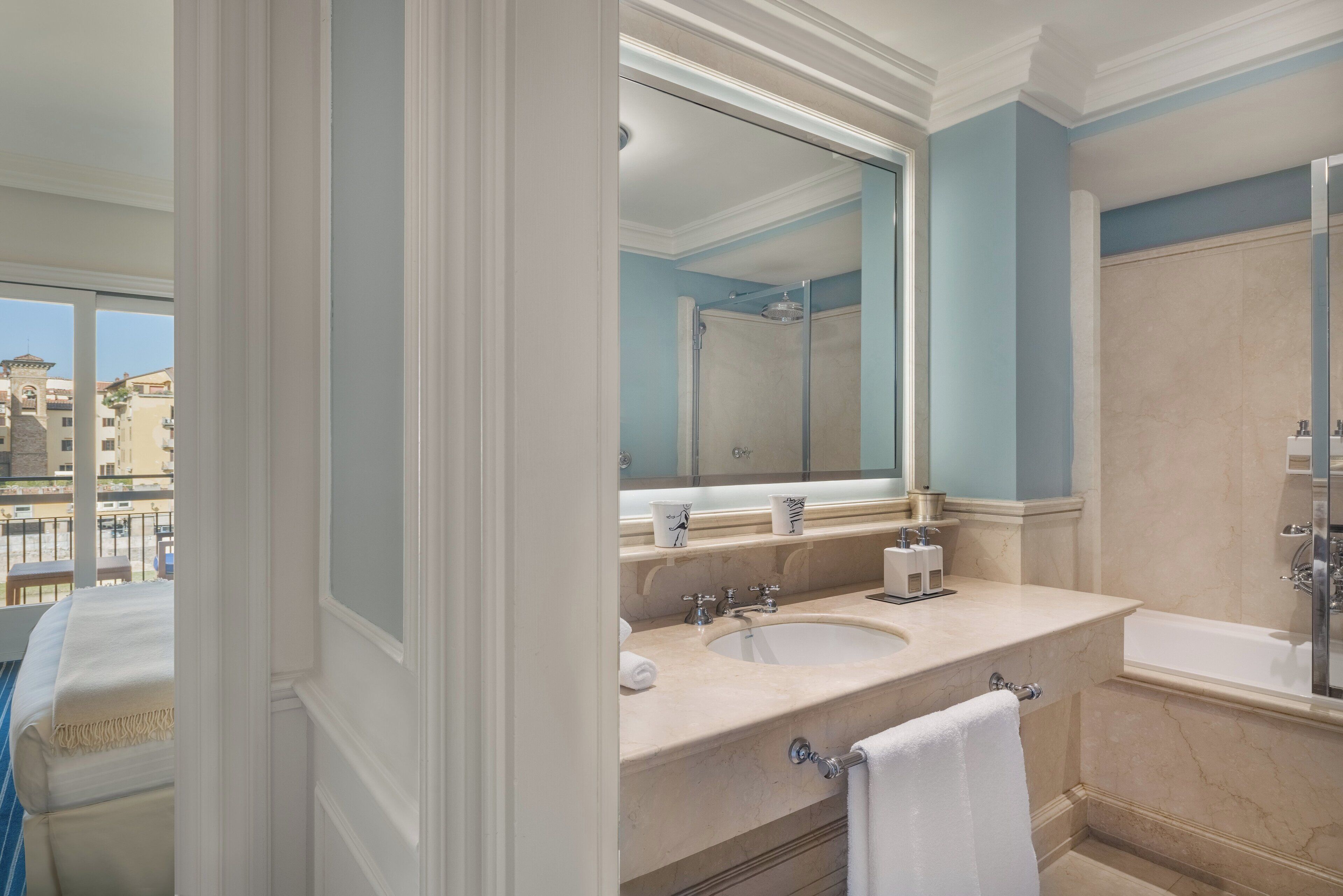A bathroom with a large mirror, two sinks, a bathtub, and a shower.