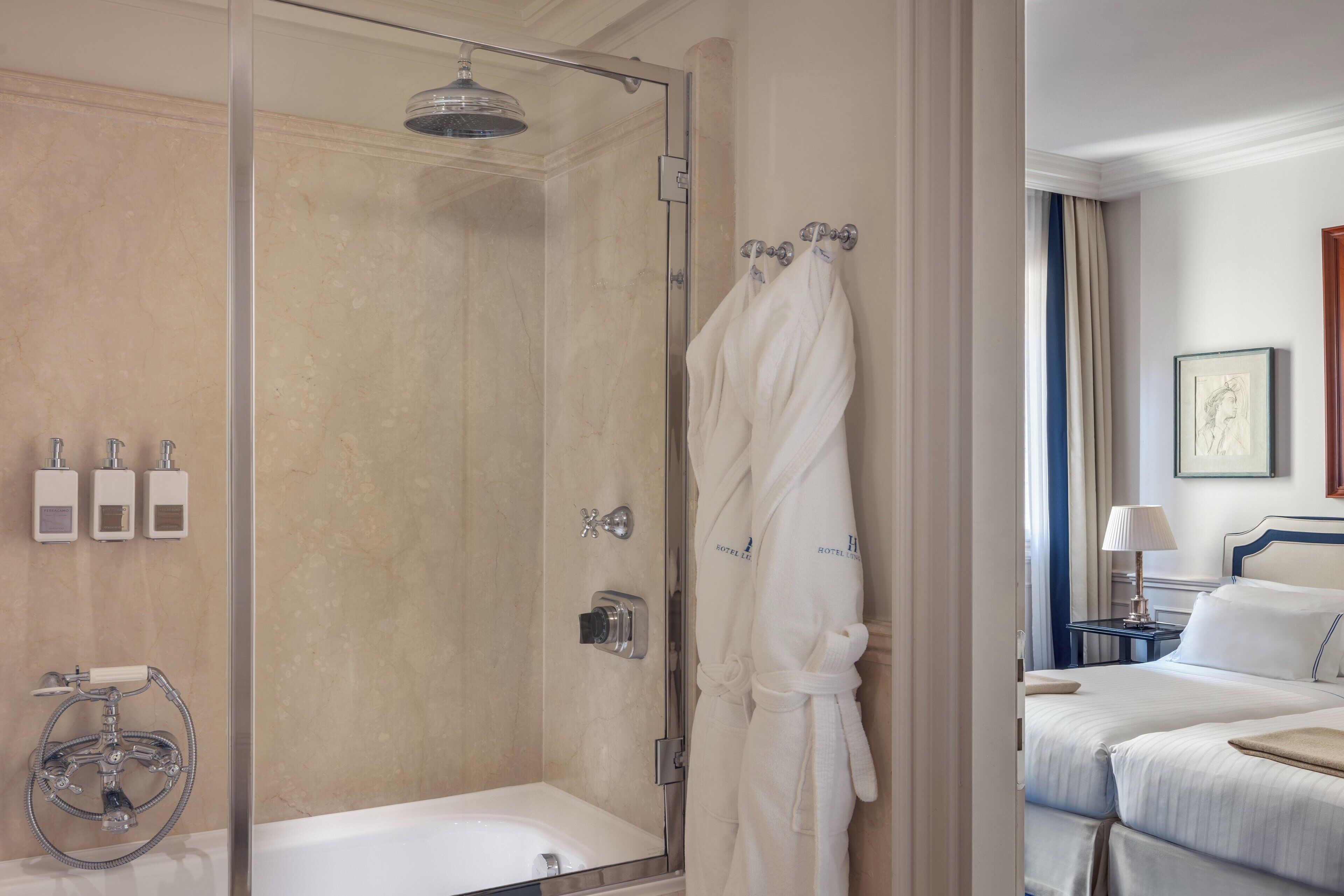 Une salle de bain d’hôtel avec une douche à parois de verre, une baignoire et un peignoir suspendu à un crochet.