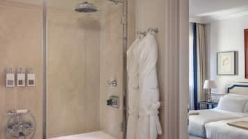 A hotel bathroom with a glass-enclosed shower, a bathtub, and a robe hanging on a hook.
