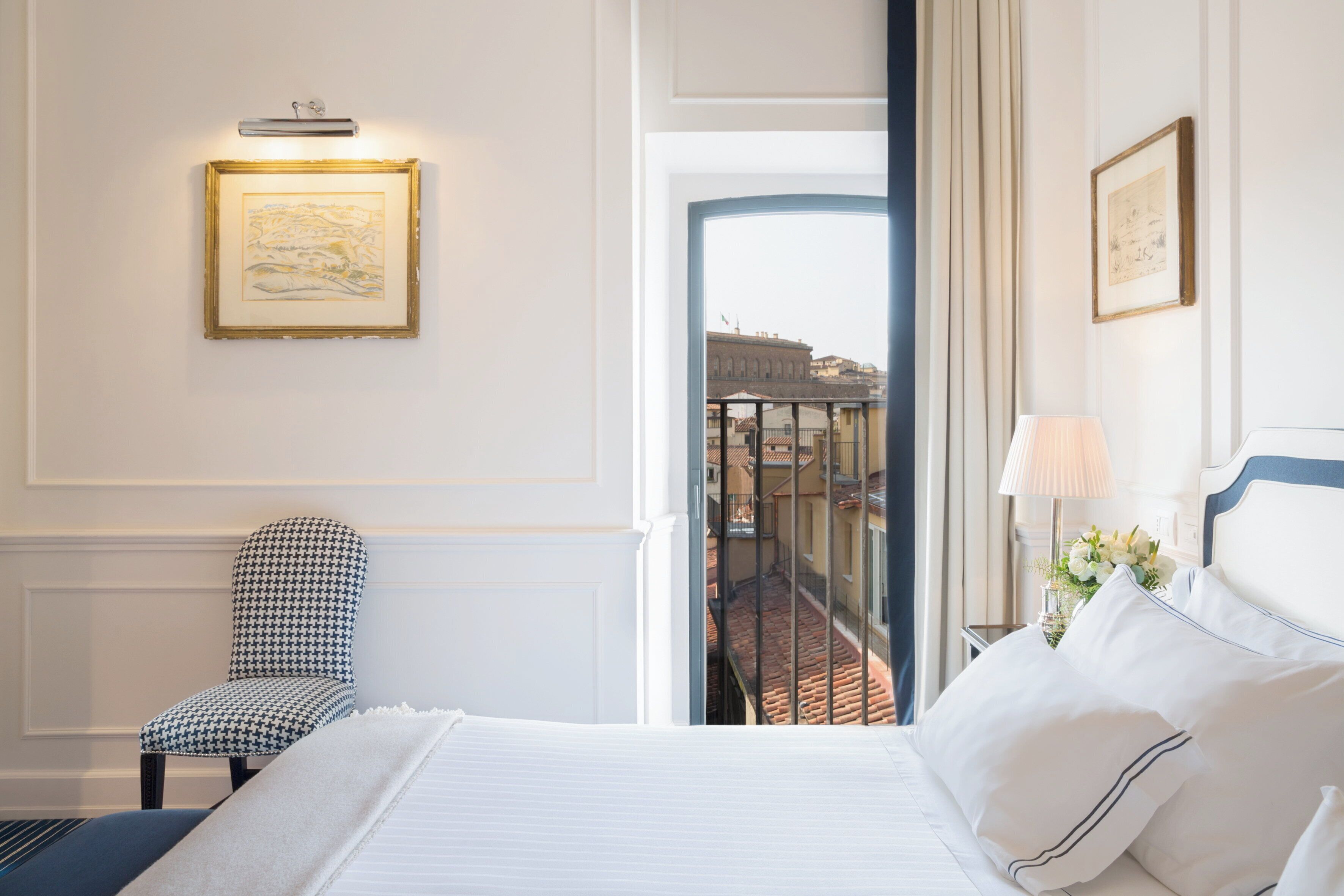 Een hotelkamer met een bed, een stoel, een nachtkastje met een lamp en lijstwerken aan de wanden.